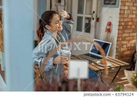 Cute modern girl sitting at a computer outdoors Cute modern girl sitting at a computer outdoors 63794124