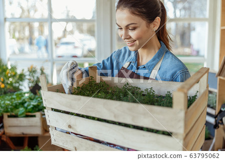Lovely female botanist admiring her green plants Lovely female botanist admiring her green plants 63795062