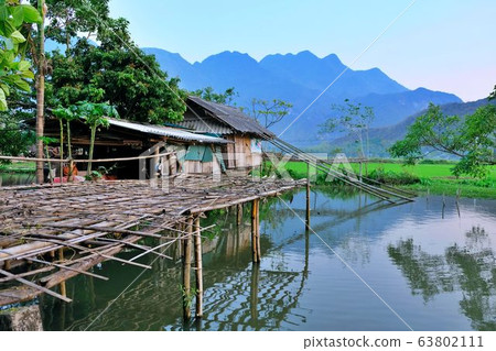 A lake and the bamboo house in the village of the ethnic minority people in Mai Chau, Hoa Binh, Vietnam A lake and the bamboo house in the village of the ethnic minority people in Mai Chau, Hoa Binh, Vietnam 63802111