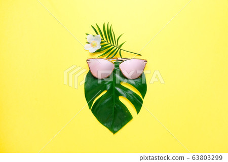 Tropical beach concept. Fashionable hipster Monstera in trendy glasses. Creative poster is bright yellow. copy space Tropical beach concept. Fashionable hipster Monstera in trendy glasses. Creative poster is bright yellow. copy space 63803299