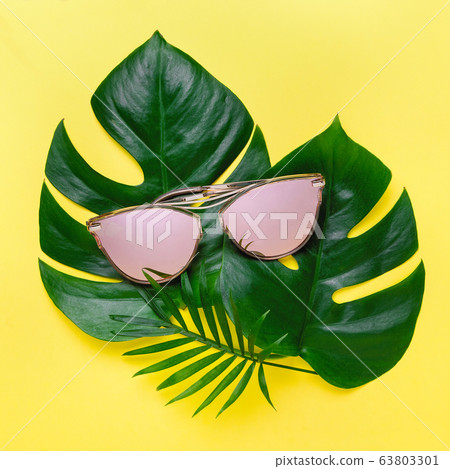 Summer composition of tropical palm leaves, Monstera. yellow background with pink glasses. Concept - Summer vacation 63803301