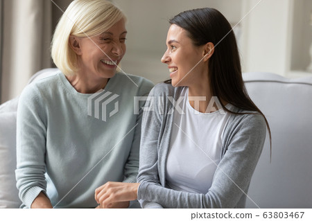 Happy elderly mother and adult daughter relax at home talking 63803467