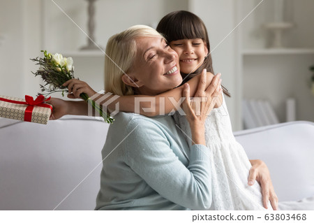 Loving little grandchild congratulate senior granny with flowers 63803468