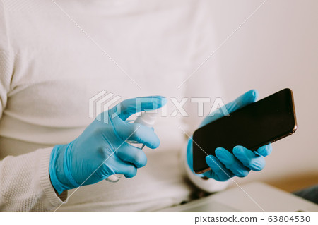 man desinfecting smarphone with aniseptic gel 63804530