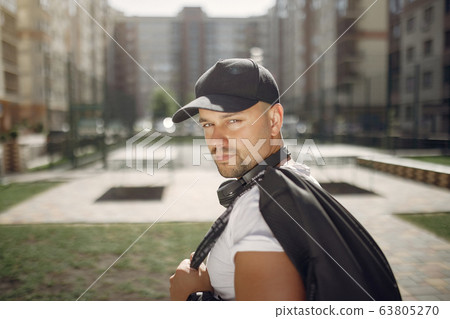 Handsome man standing in a park with a headphones 63805270