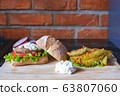 Homemade burger with beef chop, tomato, lettuce and dorblu blue cheese sauce. Serve on a wooden kitchen board on a table made of natural stone. Background image. 63807060