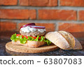 Homemade burger with beef chop, tomato, lettuce and dorblu blue cheese sauce. Serve on a wooden kitchen board on a table made of natural stone. Background image. 63807083