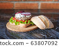 Homemade burger with beef chop, tomato, lettuce and dorblu blue cheese sauce. Serve on a wooden kitchen board on a table made of natural stone. Background image. 63807092