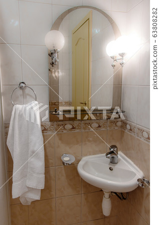 A sink with a mirror lit by a lamp in a small A sink with a mirror lit by a lamp in a small 63808282