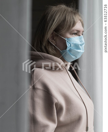 Portrait of senior woman in medical mask near the window 63812716