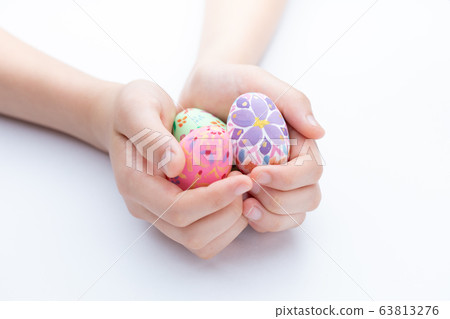 手工復活節彩蛋騎在孩子的手掌上 63813276