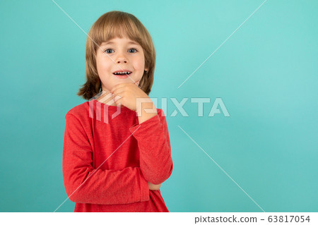 sweet european boy in red sweater posing on isolated blue studio background sweet european boy in red sweater posing on isolated blue studio background 63817054