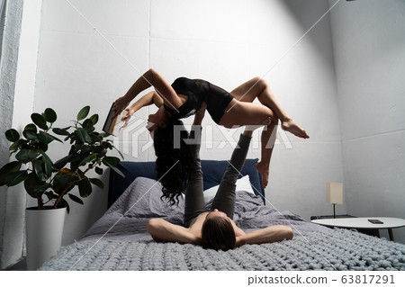 Couple spending time together reading book and making acrobatic balance at home. concept of self-development and creativity. Couple spending time together reading book and making acrobatic balance at home. concept of self-development and creativity. 63817291