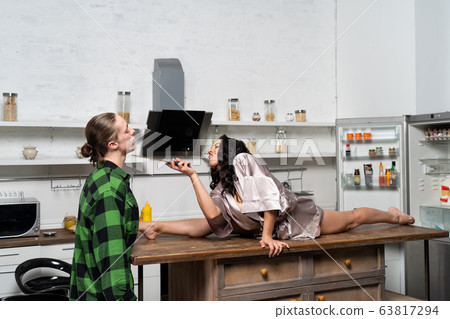 woman flirting in the kitchen with man by dangerous way with knife. woman flirting in the kitchen with man by dangerous way with knife. 63817294