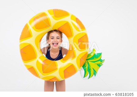 teenager girl in swimming clothes among swimming circles and mattresses on vacation on an isolated teenager girl in swimming clothes among swimming circles and mattresses on vacation on an isolated 63818105