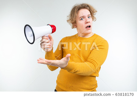 blond wavy guy shouting news into a loudspeaker on a white studio background blond wavy guy shouting news into a loudspeaker on a white studio background 63818170