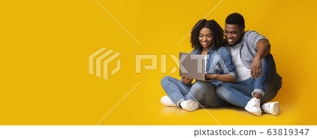 African american couple using laptop while sitting on floor in studio 63819347