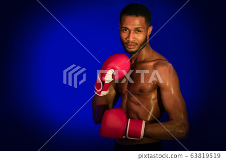 Professional African Boxer In Gloves Posing Over Blue Studio Background 63819519