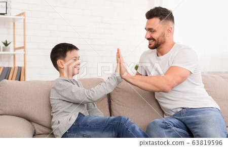 Father and son giving high five to each other at home Father and son giving high five to each other at home 63819596