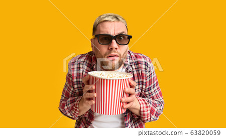 Emotional excitement from film. Funny guy hiding behind popcorn 63820059