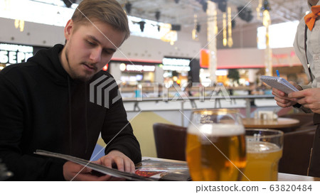 Young bearded man looking at menu in a restaurant Young bearded man looking at menu in a restaurant 63820484
