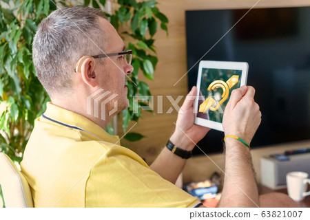 Man wearing deaf aid with tablet 63821007