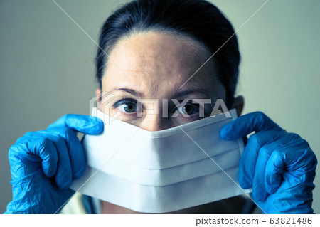 portrait of female doctor wearing protective mask and looking at camera posing against white background portrait of female doctor wearing protective mask and looking at camera posing against white background 63821486