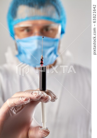 Close up hand holding syringe with dark red blood. Close up hand holding syringe with dark red blood. 63821642