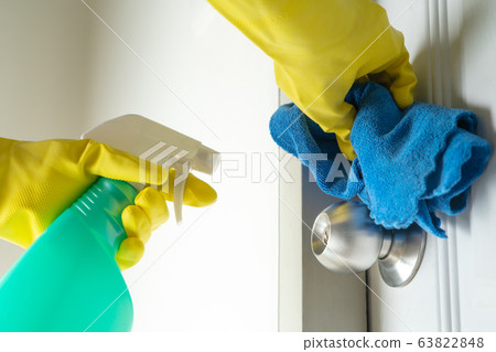 Cleaning door knob with alcohol spray for Covid-19 Coronavirus prevention Cleaning door knob with alcohol spray for Covid-19 Coronavirus prevention 63822848