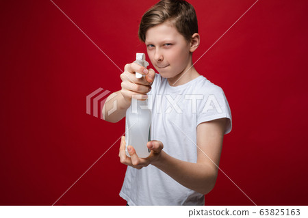 Portrait of fearless teenage male holding spray 63825163