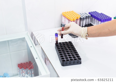 Covid-19, coronavirus, pandemic and viruses concept - hand holding blood in tests tubes in laboratory. Covid-19, coronavirus, pandemic and viruses concept - hand holding blood in tests tubes in laboratory. 63825211