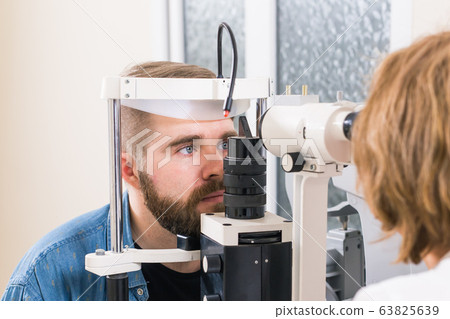 Medicine, health, ophthalmology concept - patient checks her vision by an ophthalmologist. Medicine, health, ophthalmology concept - patient checks her vision by an ophthalmologist. 63825639