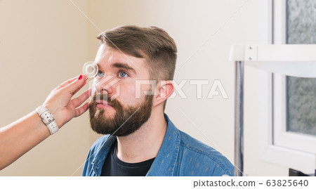 Medicine, health, ophthalmology concept - Ophthalmologist examines patient's eyes. Medicine, health, ophthalmology concept - Ophthalmologist examines patient's eyes. 63825640