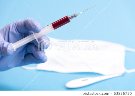 Medical blue mask on a blue background. Medical instruments for medical professionals in surgery and medical procedures. Disposable syringe and medicine vials. Coronavirus in China Medical blue mask on a blue background. Medical instruments for medical professionals in surgery and medical procedures. Disposable syringe and medicine vials. Coronavirus in China 63826730