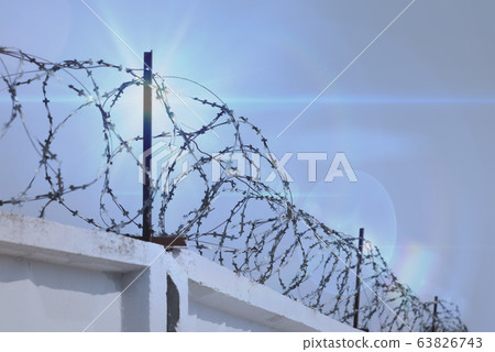 Barbed wire fence against the blue sky 63826743