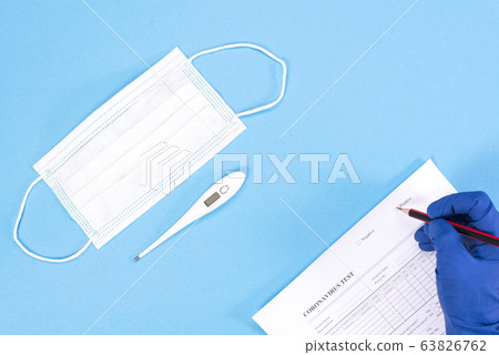 A doctor is conducting a coronovirus test. Doctor's hands with mask and thermometer on a blue background 63826762