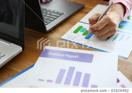 On girls desk is laptop and statistical reports 63826982