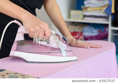 Girl ironing cloth on an ironing board, close-up 63827037