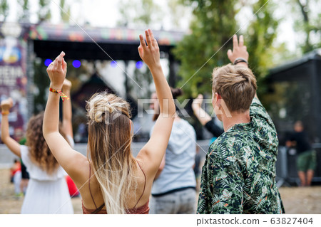Rear view of group of young friends dancing at summer festival. 63827404