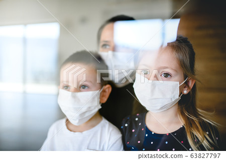 Mother and children with face masks indoors at home, Corona virus, quarantine concept. Mother and children with face masks indoors at home, Corona virus, quarantine concept. 63827797