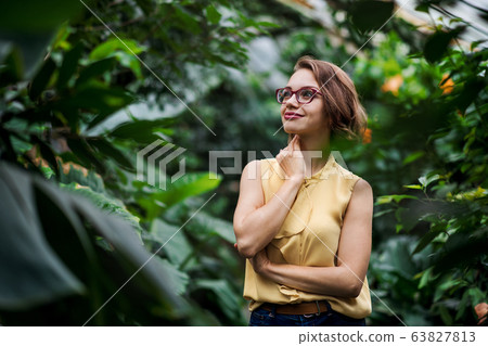 Young woman standing in botanical garden. Copy space. Young woman standing in botanical garden. Copy space. 63827813