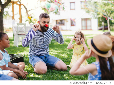 Man with small children on ground outdoors in garden in summer, playing. Man with small children on ground outdoors in garden in summer, playing. 63827827