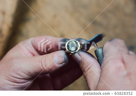 Closeup on hands of goldsmith working on a ring in his workshop Closeup on hands of goldsmith working on a ring in his workshop 63828352