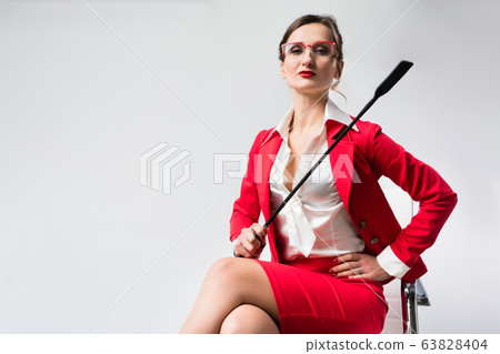 Arrogant businesswoman with a whip in her chair Arrogant businesswoman with a whip in her chair 63828404