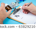 Male doctor or pharmacist holding jar or bottle of pills in hand and writing prescription on a special form. medical costs and healthcare payment concept. 63829210