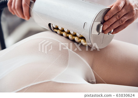 Masseur makes apparatus anti-cellulite massage in the cosmetology clinic Masseur makes apparatus anti-cellulite massage in the cosmetology clinic 63830624