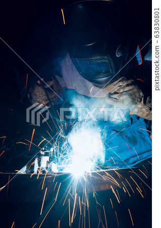 Locksmith in special clothes and goggles works in production. Metal processing with angle grinder. Sparks in metalworking Locksmith in special clothes and goggles works in production. Metal processing with angle grinder. Sparks in metalworking 63830801