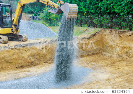 Excavator with a bucket lowered down gravel stones Excavator with a bucket lowered down gravel stones 63834564