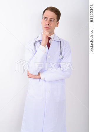Young handsome man doctor against white background Young handsome man doctor against white background 63835348