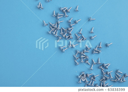Many screws on blue paper, blurred background Many screws on blue paper, blurred background 63838399